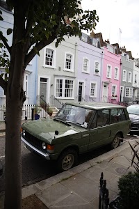 Green Range Rover parked on a colorful street in London