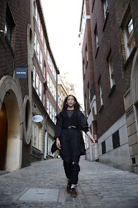 Urban Golden Hour Portrait — Young Woman in Black Against Glass Building