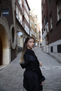 Urban Golden Hour Portrait — Young Woman in Black Against Glass Building