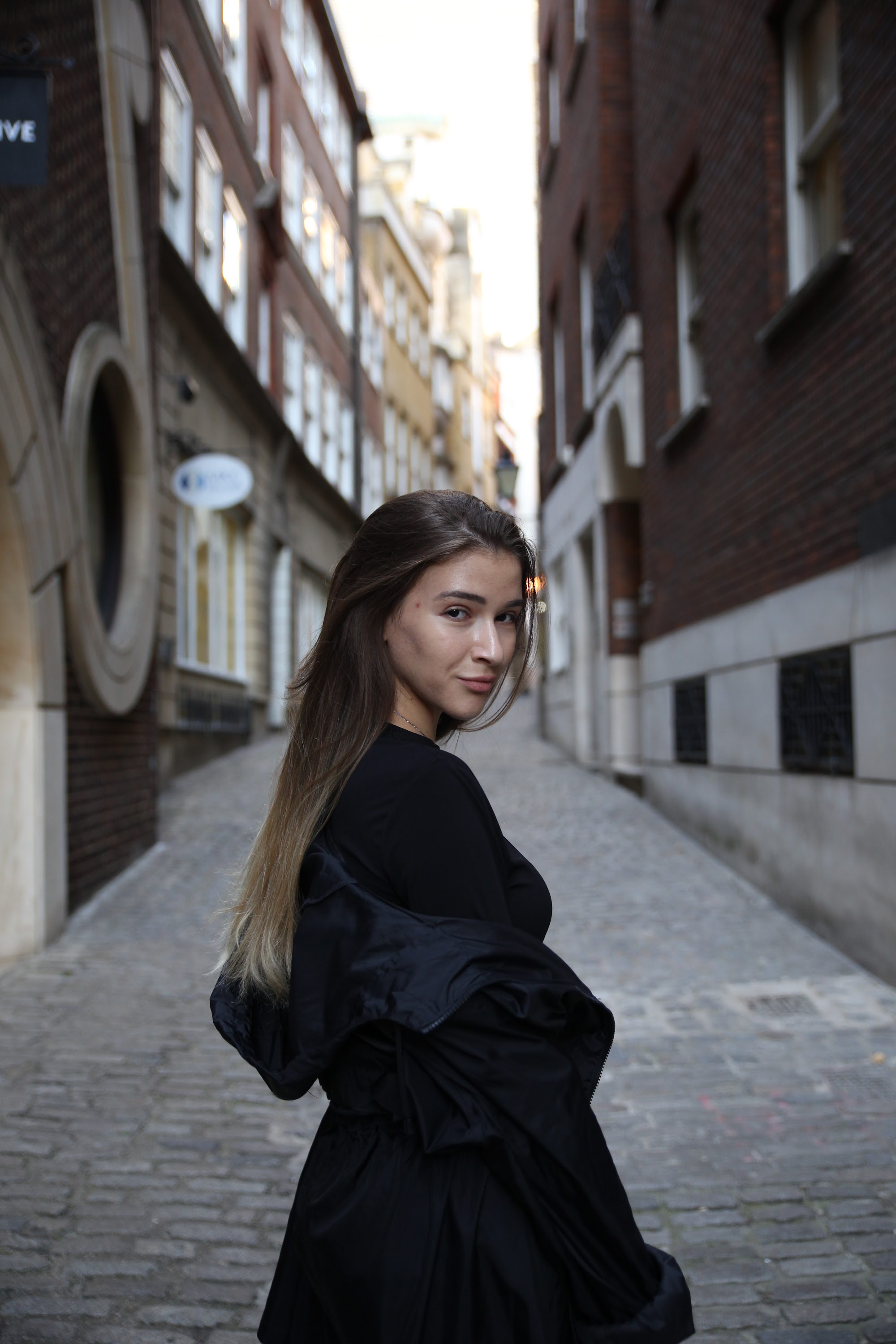 Urban Golden Hour Portrait — Young Woman in Black Against Glass Building