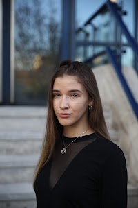 Urban Golden Hour Portrait — Young Woman in Black Against Glass Building