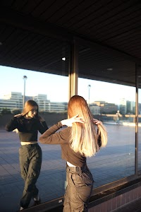 Urban Golden Hour Portrait — Young Woman in Black Against Glass Building
