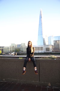Urban Golden Hour Portrait — Young Woman in Black Against Glass Building
