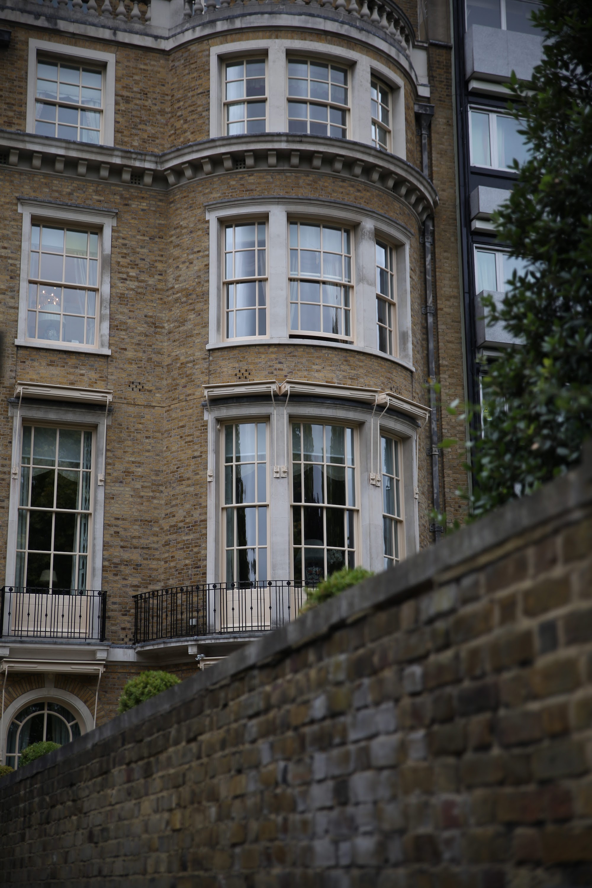 Victorian-style brick building with bay windows and wrought-iron balcony