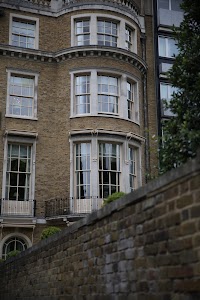 Victorian-style brick building with bay windows and wrought-iron balcony