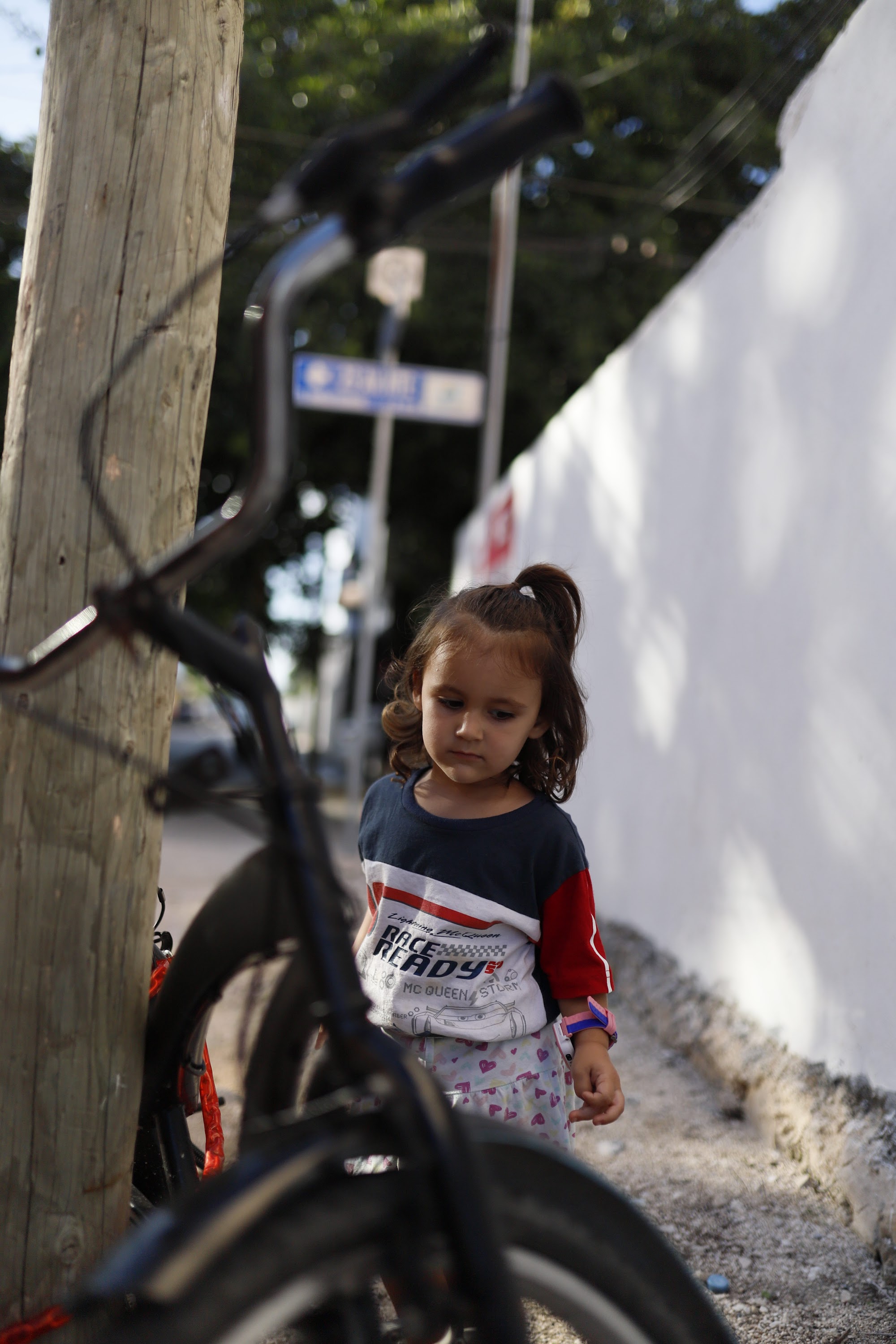 Young Girl Standing Near Bicycle on Street