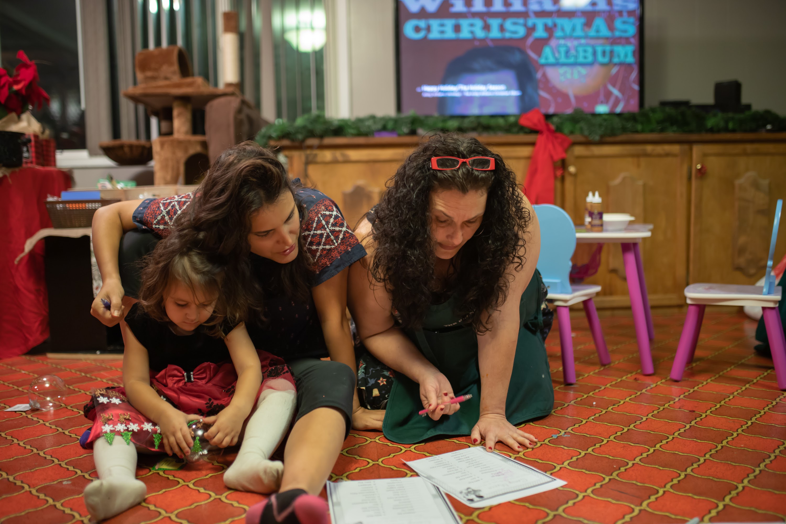 Women and Child Engaged in Holiday Activity at Indoor Event