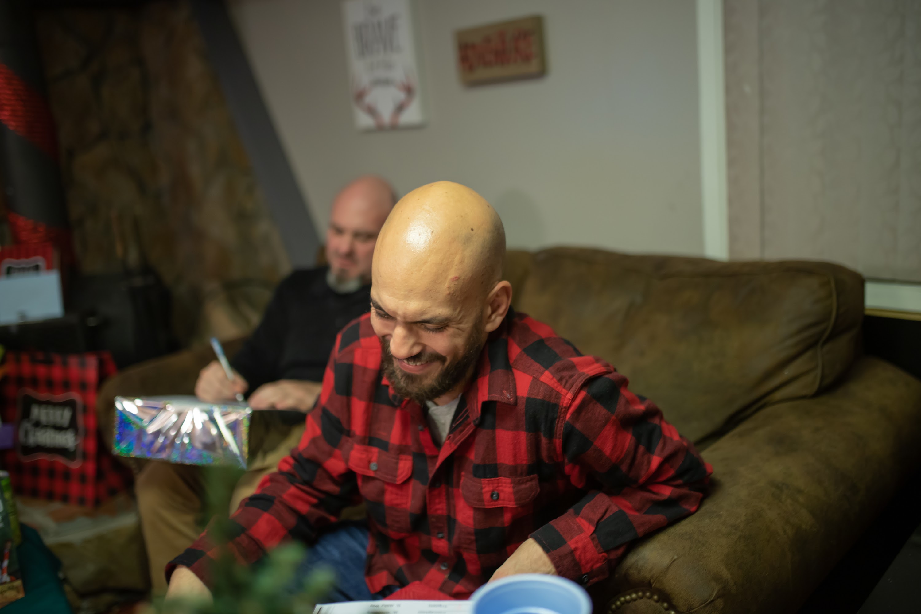 Bald Man in Red Plaid Shirt Laughing on Couch