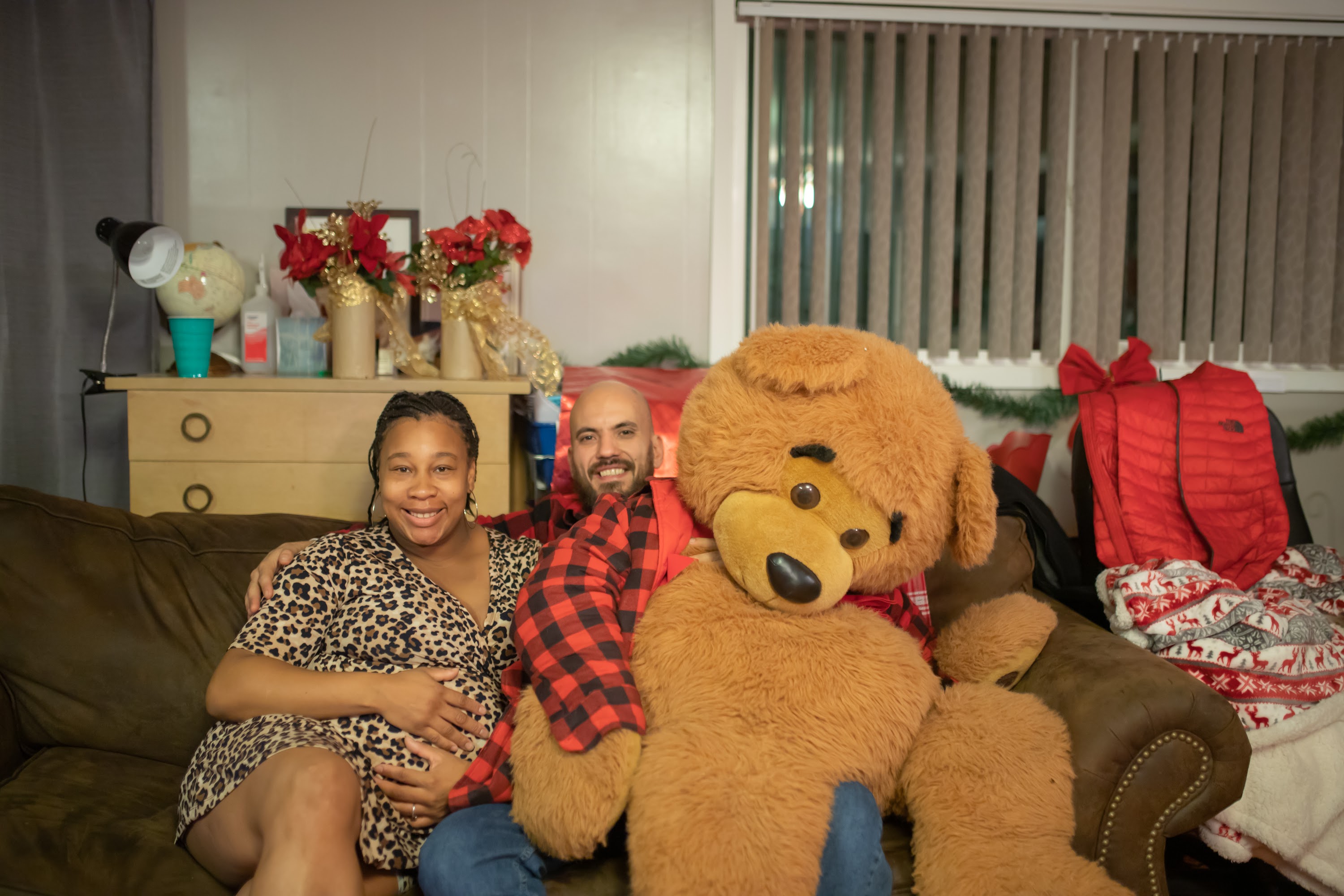 Pregnant Woman and Man Posed with Giant Teddy Bear on Couch