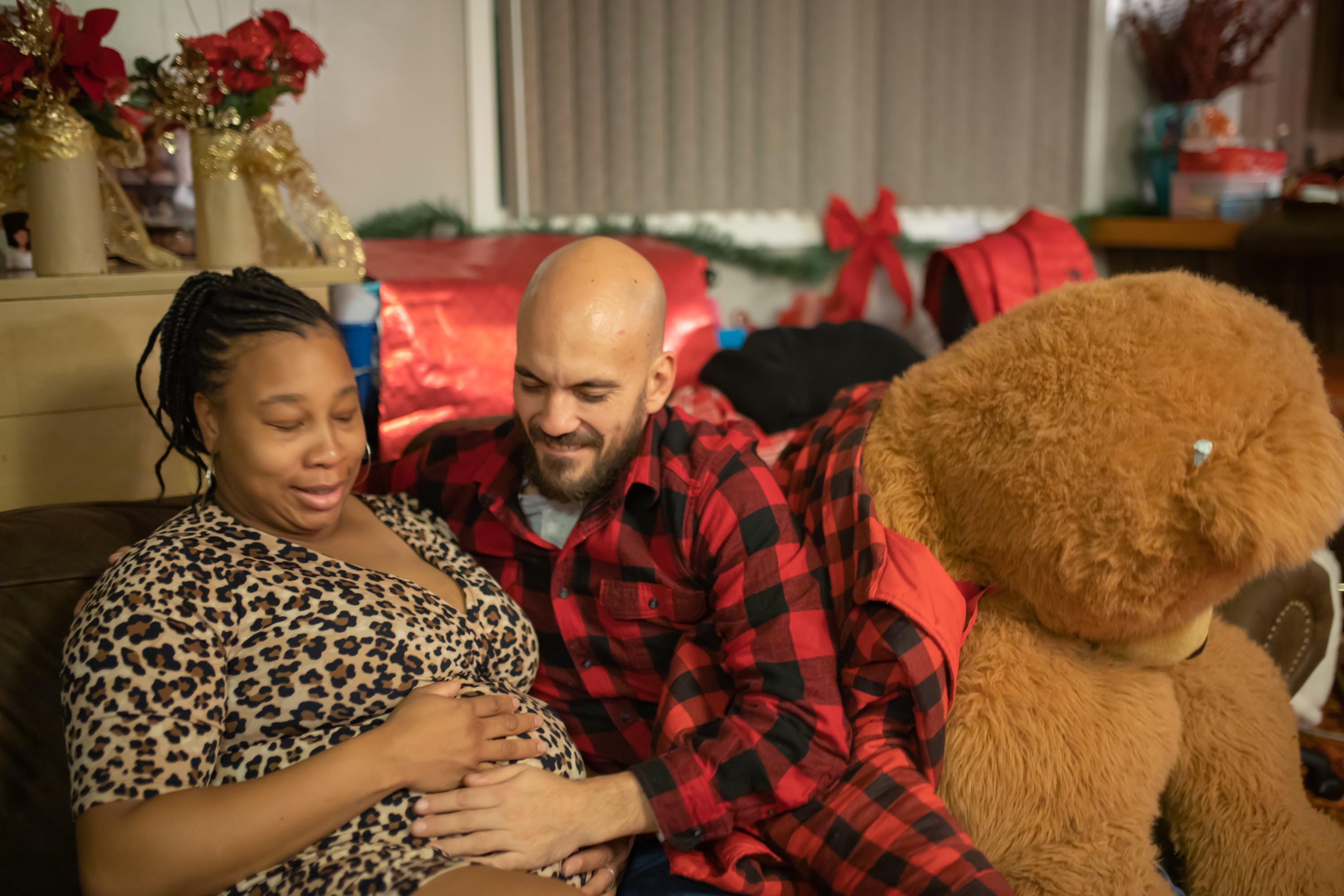 Pregnant Woman and Partner Sharing a Moment with a Large Teddy Bear