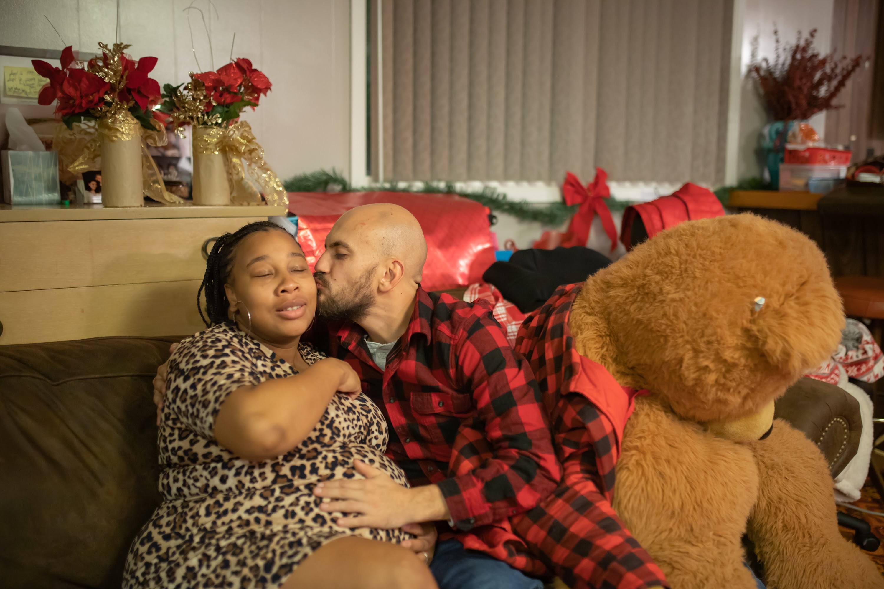 Pregnant Woman and Partner Sharing a Tender Moment on Couch with Holiday Decor