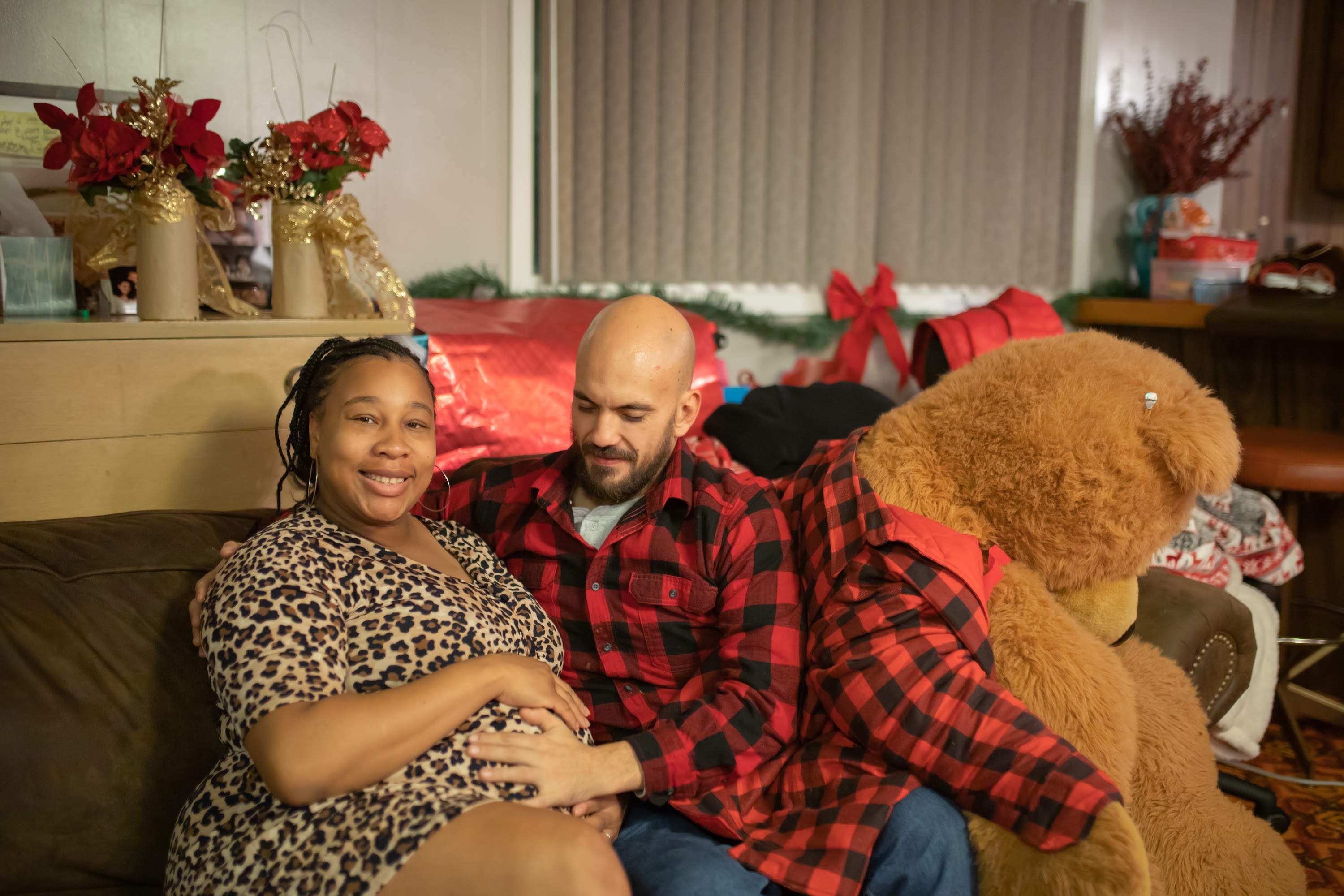 Pregnant Couple Relaxing on Couch with Giant Teddy Bear
