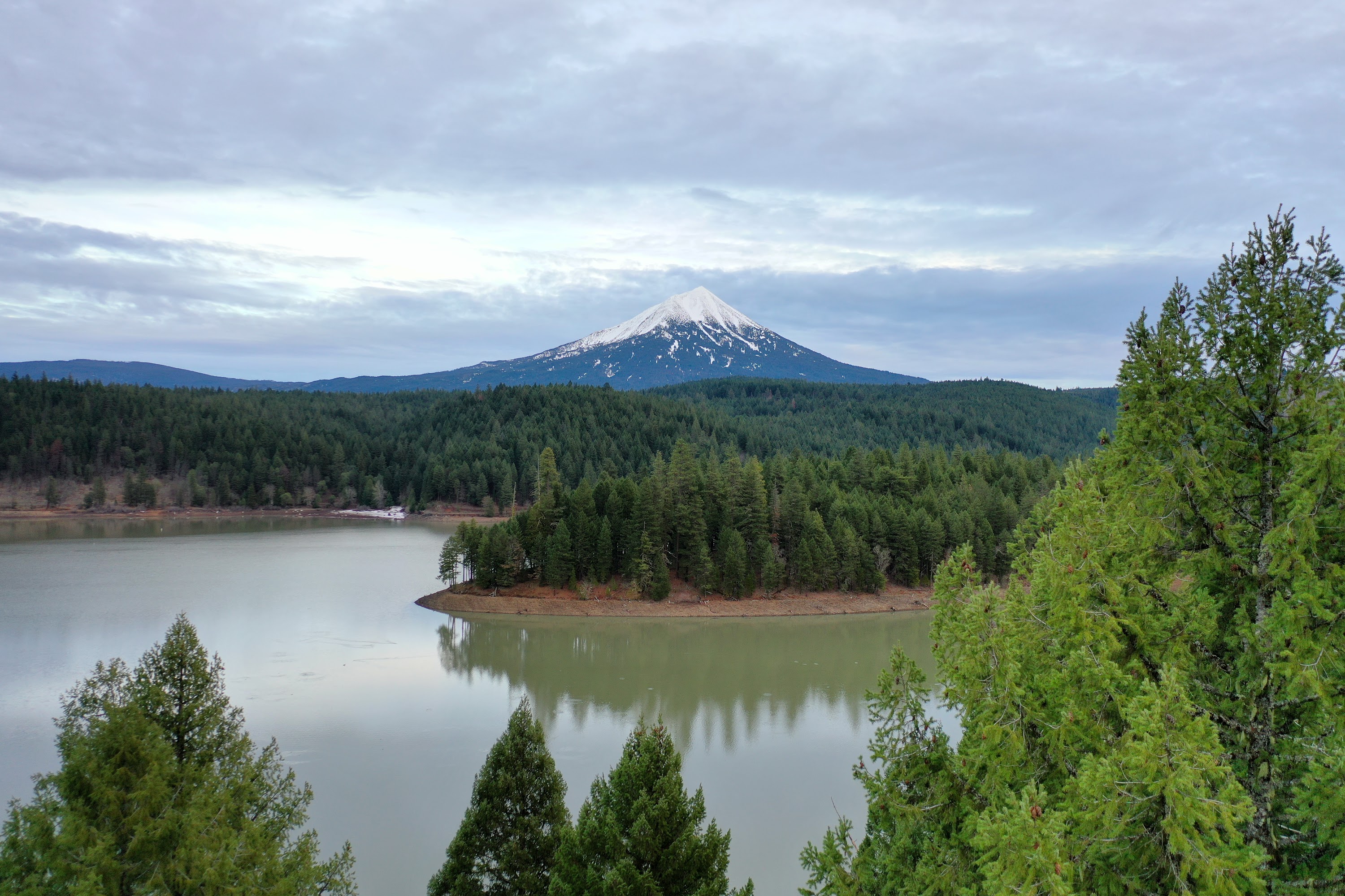 Snow-Capped Mountain Reflecting in Calm Lake Surrounded by Forest