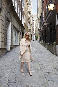 Blonde Woman in Beige Trench Coat on Cobblestone Alley