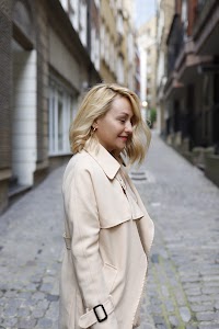 Blonde Woman in Beige Trench Coat on Cobblestone Alley
