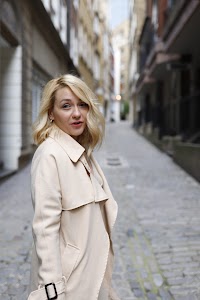 Blonde Woman in Beige Trench Coat on Cobblestone Alley