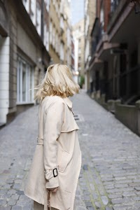 Blonde Woman in Beige Trench Coat on Cobblestone Alley