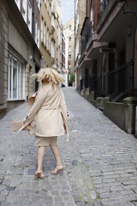 Blonde Woman in Beige Trench Coat on Cobblestone Alley