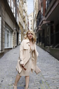 Blonde Woman in Beige Trench Coat on Cobblestone Alley
