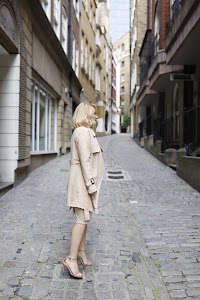 Blonde Woman in Beige Trench Coat on Cobblestone Alley