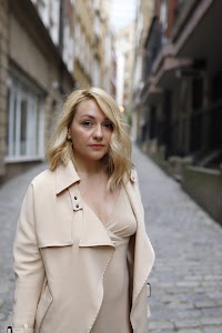 Blonde Woman in Beige Trench Coat on Cobblestone Alley