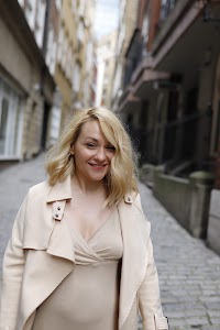 Blonde Woman in Beige Trench Coat on Cobblestone Alley