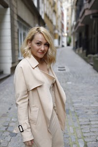 Blonde Woman in Beige Trench Coat on Cobblestone Alley