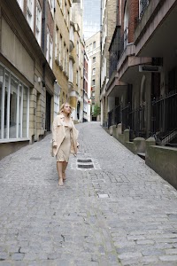 Blonde Woman in Beige Trench Coat on Cobblestone Alley