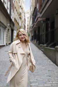 Blonde Woman in Beige Trench Coat on Cobblestone Alley