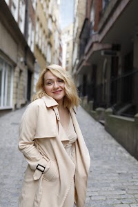 Blonde Woman in Beige Trench Coat on Cobblestone Alley