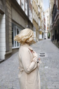 Blonde Woman in Beige Trench Coat on Cobblestone Alley