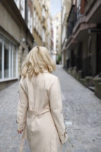 Blonde Woman in Beige Trench Coat on Cobblestone Alley