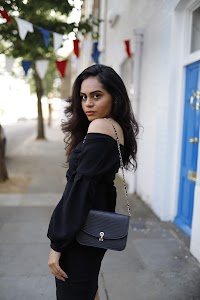 Woman in Off-Shoulder Black Dress on Urban Sidewalk