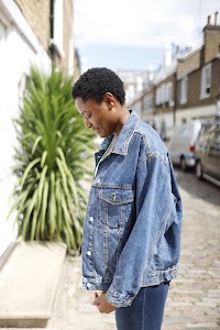 Laughing Young Woman in Denim Jacket Beside Flowering Bush