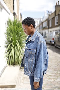 Laughing Young Woman in Denim Jacket Beside Flowering Bush