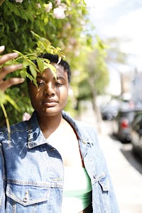 Laughing Young Woman in Denim Jacket Beside Flowering Bush
