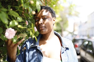 Laughing Young Woman in Denim Jacket Beside Flowering Bush