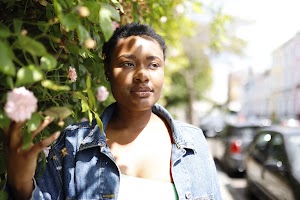Laughing Young Woman in Denim Jacket Beside Flowering Bush