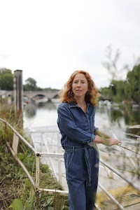 Woman Smiling Outdoors Near Stone Bridge
