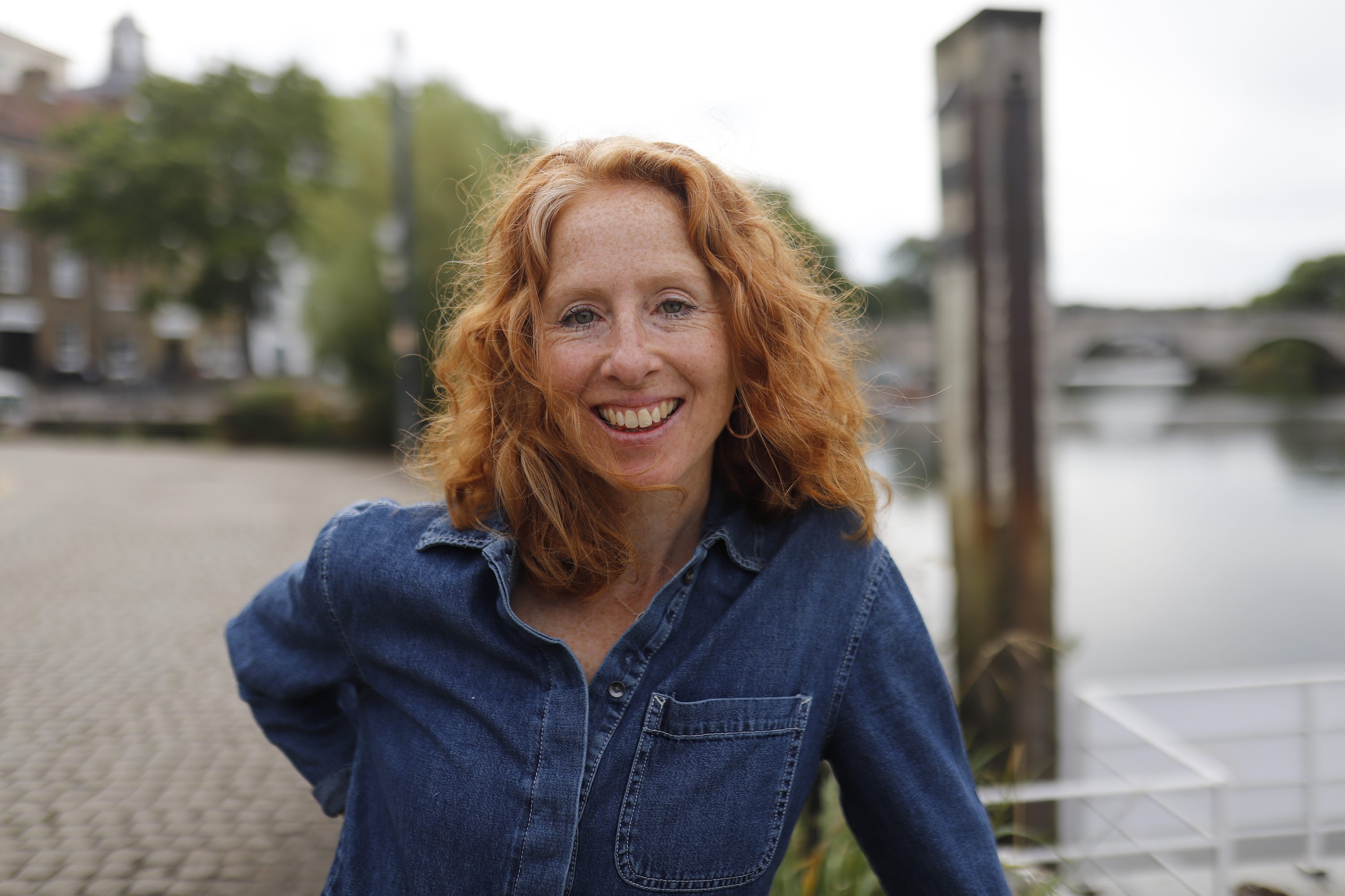 Woman Smiling Outdoors Near Stone Bridge