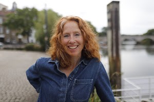 Woman Smiling Outdoors Near Stone Bridge