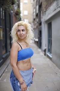 Woman Seated on Bench Outside Urban Shopfront