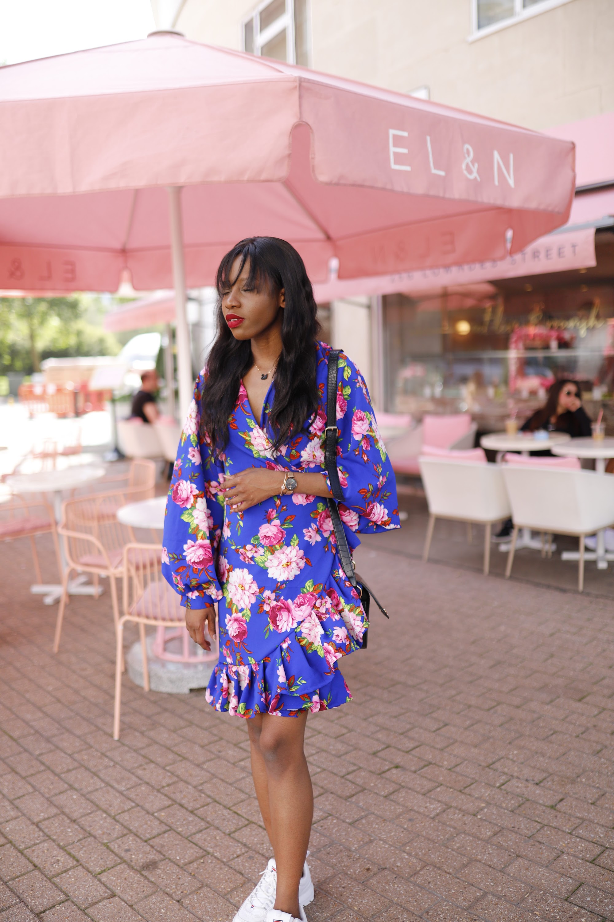 Woman in Blue Floral Wrap Dress at Pink Outdoor Terrace