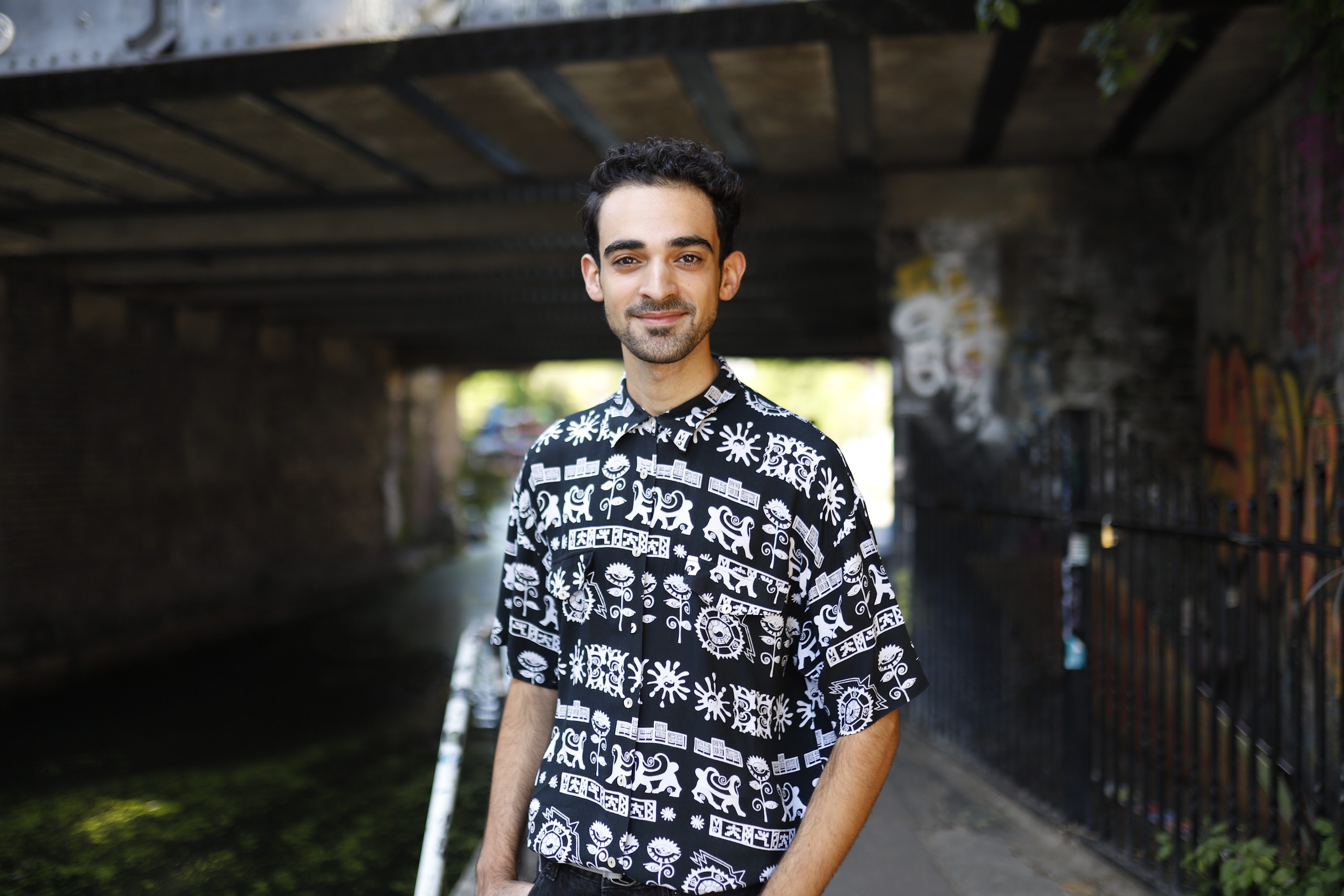 Young Man in Patterned Shirt Against Graffiti Wall