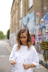 Woman in White Jacket Holding Sunglasses – Dark Urban Tunnel