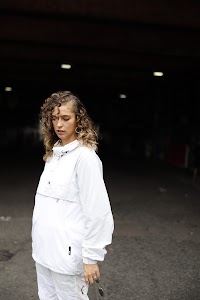 Woman in White Jacket Holding Sunglasses – Dark Urban Tunnel