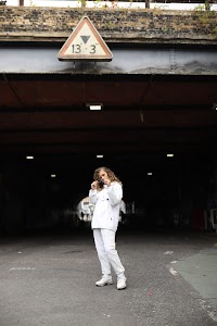 Woman in White Jacket Holding Sunglasses – Dark Urban Tunnel