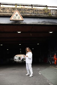 Woman in White Jacket Holding Sunglasses – Dark Urban Tunnel