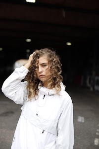 Woman in White Jacket Holding Sunglasses – Dark Urban Tunnel
