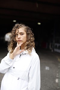 Woman in White Jacket Holding Sunglasses – Dark Urban Tunnel